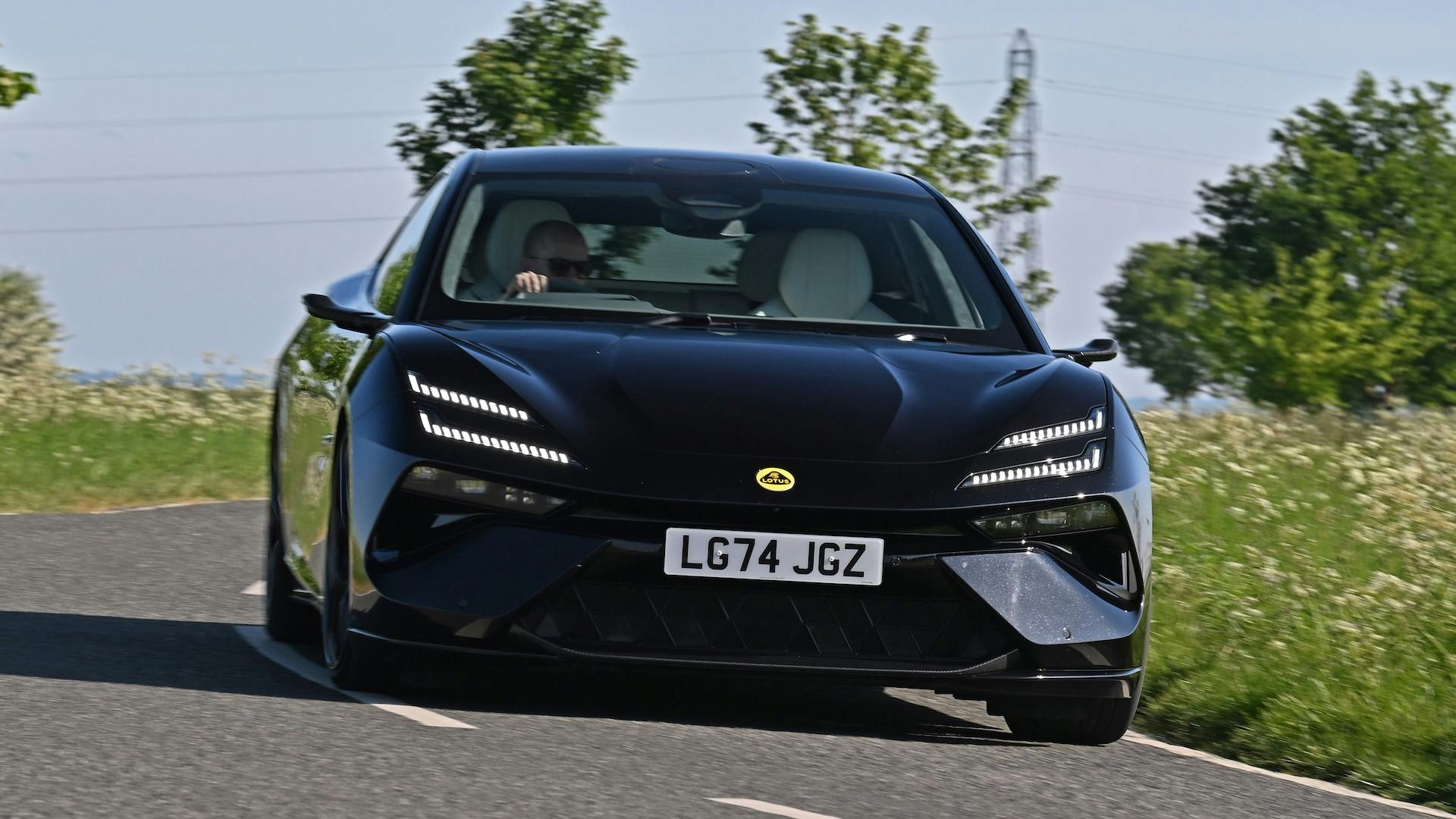 Black 2025 Lotus Emeya driving round a corner, front view.