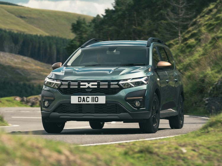 Green Dacia Jogger driving around a corner in the countryside.